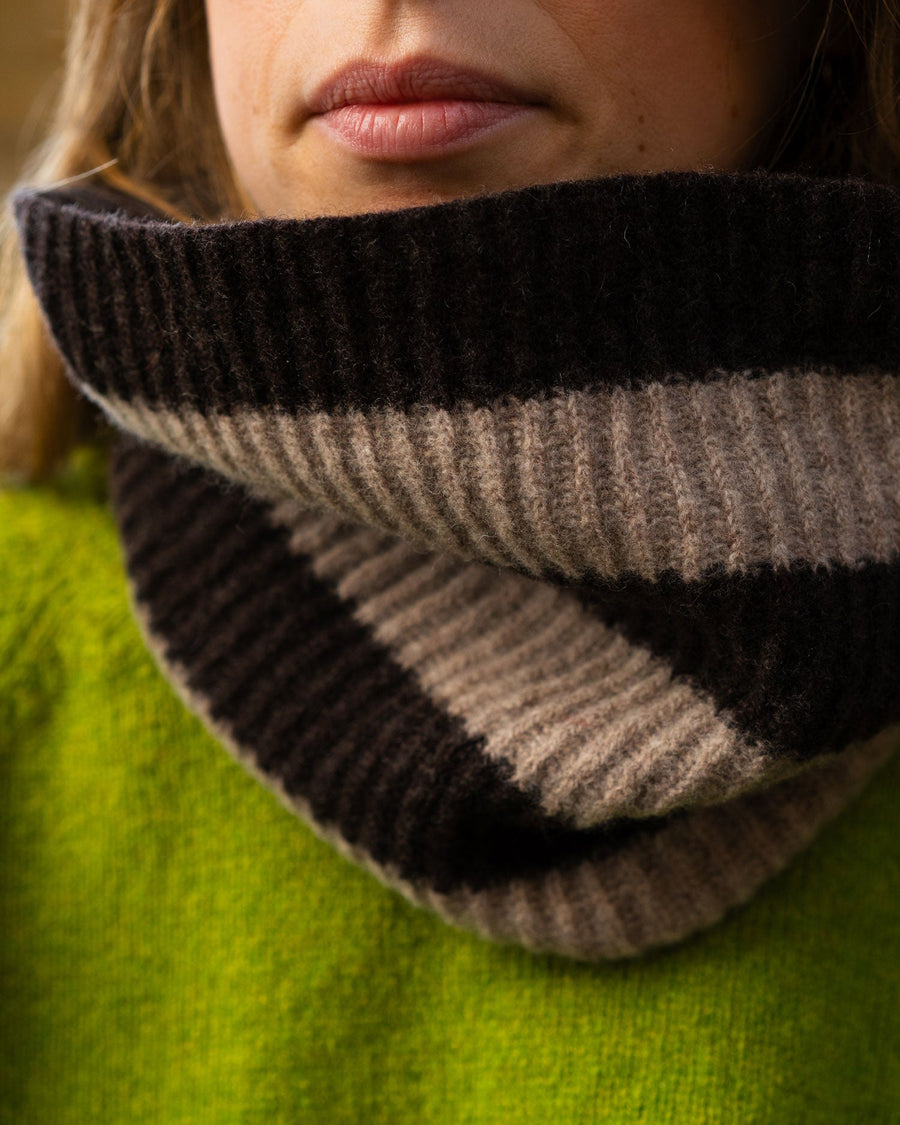 Close-up of a striped knitted cowl worn by a person with a green garment underneath.